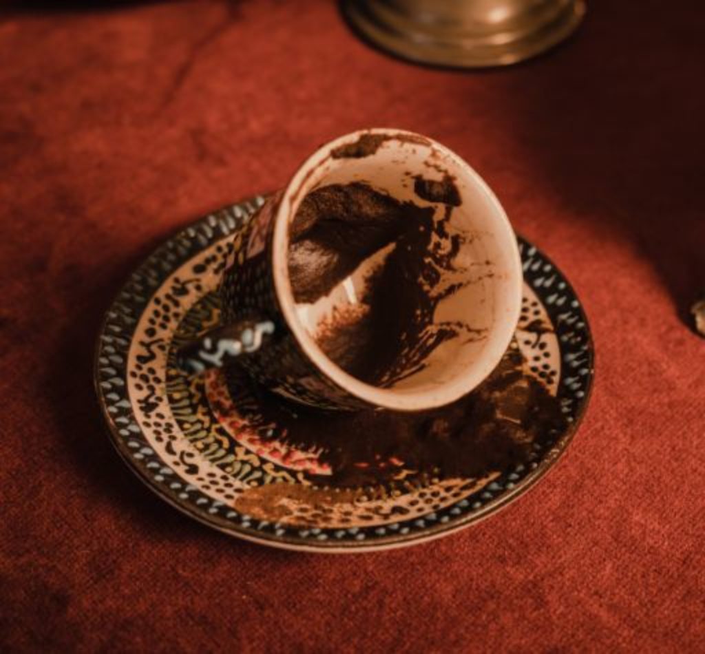 A cup tilted with a saucer displaying a Turkish Coffee Fortune Telling
